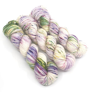 3 skeins of yarn in natural cream speckled with purple and green with speckles