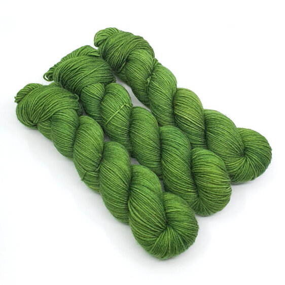 3 twisted skeins of yarn in green hues laid diagonally on a white background