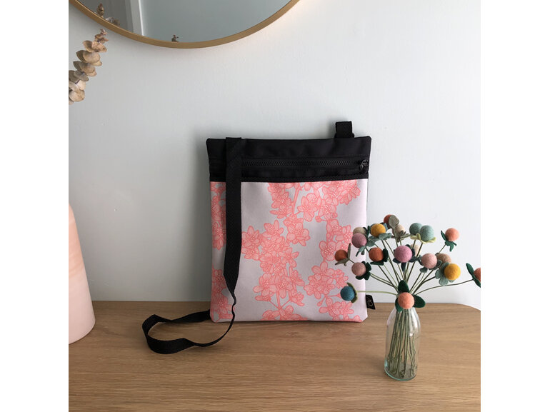 A crossbody flat fabric bag with a pocket in a cherry blossom fabric