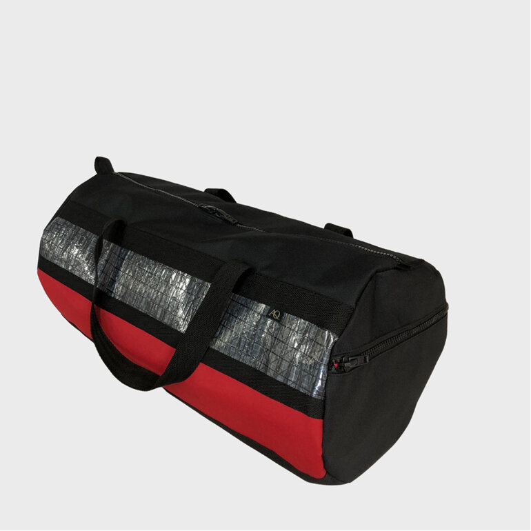 A sailing gear bag or travel bag with a carbon sailcloth feature and red