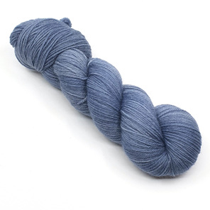 A skein of yarn in blue grey hues laid diagonally on a white background
