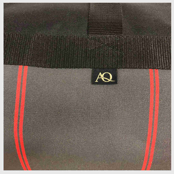An AQ gear bag made from a quality, durable fabric in red and grey.