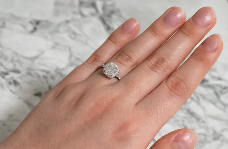 Cushion cut diamond halo cluster engagement ring on hand