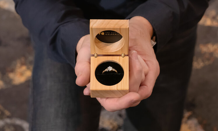engagement ring in proposal box with man holding it while on one knee