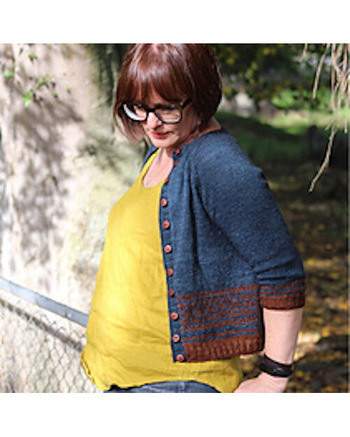 image shows a female wearing a yellow top with a blue and rust knit cardigan