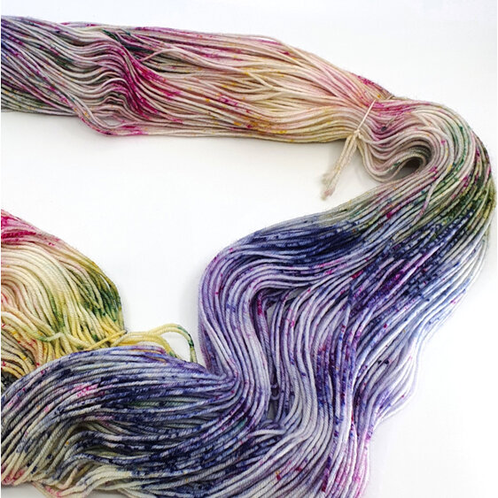 Loose skein of variegated speckled yarn in lilac, blue, green, yellow and pink