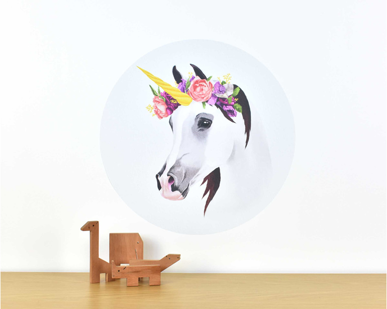 Medium unicorn wall decal with flower crown on white background with wooden toys