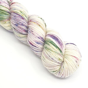 part skein of yarn in natural cream speckled with purple and green with speckles