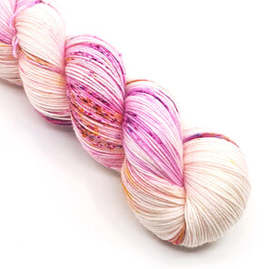 part skein of yarn in natural cream speckled with pink, gold & blue