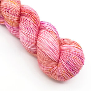 part twisted skein of yarn in apricot/peach with hot pink, gold and blue specks