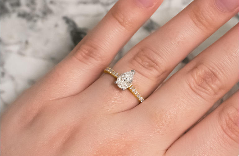 Pear cut solitaire with diamond set band, platinum and 18ct yellow gold, on hand