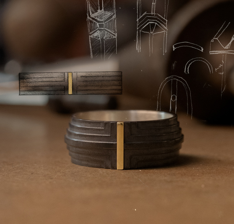 Scarpa Ring men's ring design on jeweller's work bench sketches overlay