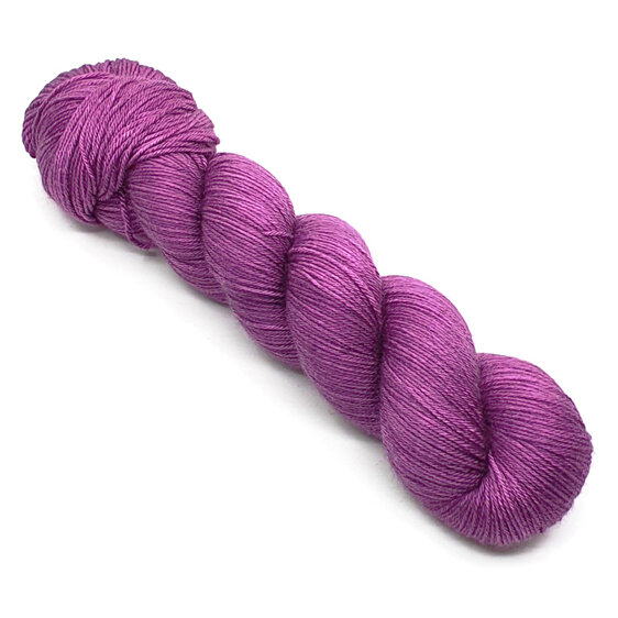 skein of 4ply merino/silk in purple hues laid diagonally on a white background