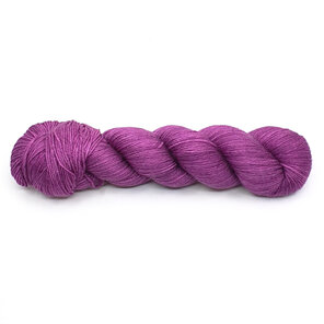 skein of 4ply merino/silk in purple hues laid horizontally on a white background