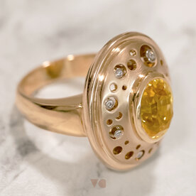 The yellow sapphire at the head of the ring orbited by small diamonds