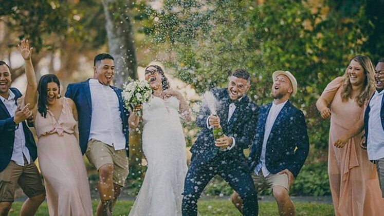 TJ and Greer popping a bottle of champagne with guests at their wedding
