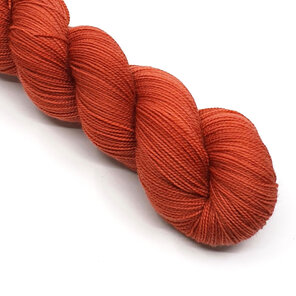 twisted skein of 4ply yarn in semi solid paprika / red ochre tones