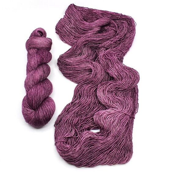 twisted skein of yarn laid to left of loose skein of 4ply merino in cabernet